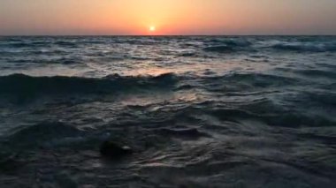 Güneşin portakal rengi ışığının çelik grideki yansımasının üzerinde gün batımı