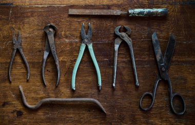 Eski ve paslı aletlerle üst kattaki ahşap manzaradan yapılmış eski bir masanın üzerinde diz çökmek