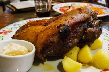 Fırında kızartılmış patates ve yaban turplu leziz domuz budu.