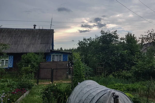 Un ciel orageux avec de la pluie entoure une petite maison en bois calme — Photo