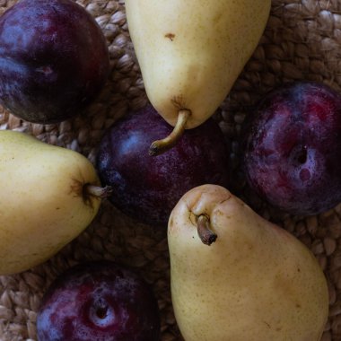 Meyve armutları ve eriklerle dolu bir hayat, tahtalardaki kaba ketenden örülmüş bir peçetenin üzerinde duvarlara karşı Provence tarzında duruyor.