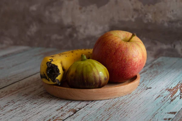 Stillleben mit Früchten liegen auf einem Holzteller, der auf Brettern im Stil der Provence an der Wand steht. — Stockfoto