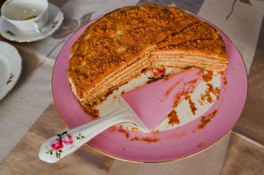 Taze hazırlanmış ballı turta ve bir spatulayla porselen tabağı doldurmak.