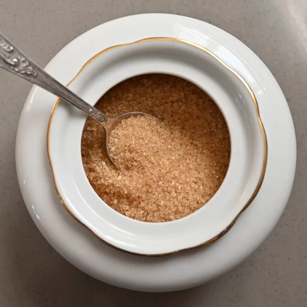 숟가락으로 설탕을 넣은 자기 설탕 그릇에 설탕을 넣는다 — 스톡 사진