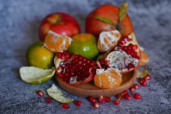 Ein Granatapfel, ganz und mit anderen Früchten in Stücke gebrochen, liegt auf einem Marmortisch — Stockfoto