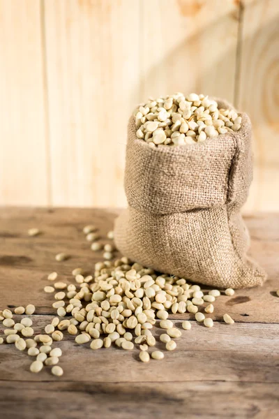 raw coffee beans in sack on wooden table