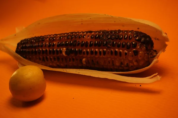 Koçandaki mısırlar geleneksel, kırsal bir pişirme düzeninde parlayan kırmızı közler üzerinde kızartılıyor..