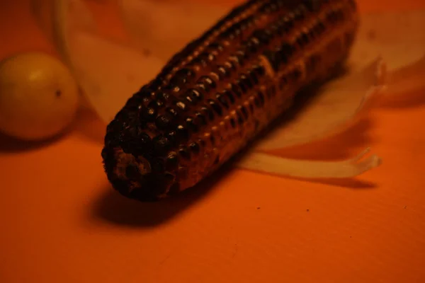 Koçandaki mısırlar geleneksel, kırsal bir pişirme düzeninde parlayan kırmızı közler üzerinde kızartılıyor..