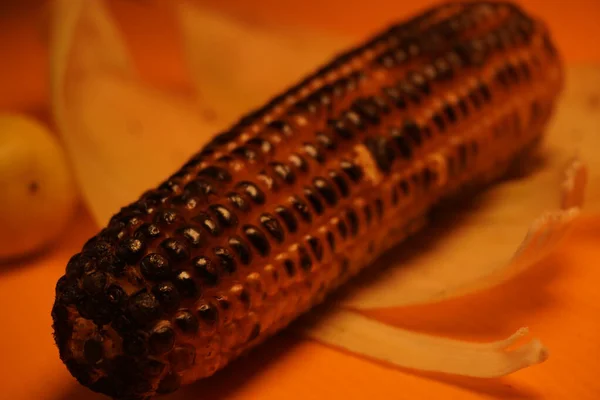 Koçandaki mısırlar geleneksel, kırsal bir pişirme düzeninde parlayan kırmızı közler üzerinde kızartılıyor..