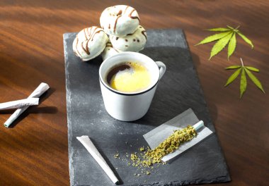 Mükemmel kahvaltı: marihuana eklemli tepsi, taze kahve ve ahşap masada çikolatalı çörek..