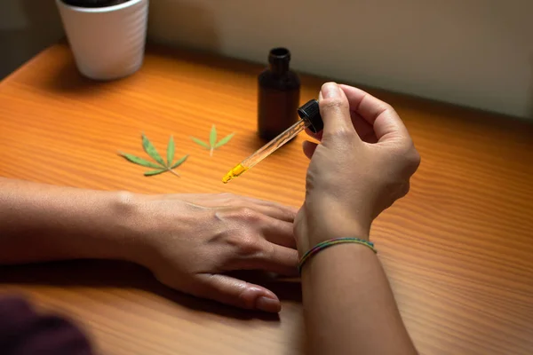 Kadın eline CBD yağı döküyor. CBD özü, marihuanayla yapılan doğal cilt bakımı ürünü..