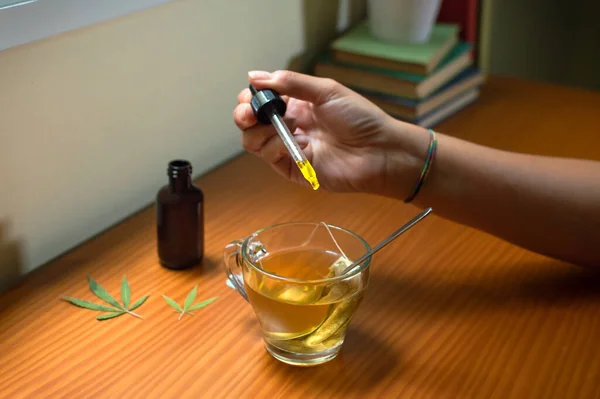 Evde sıcak bir çaya CBD yağı dökmek. Doğal marihuana ilacı kullanarak.,