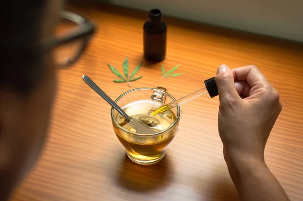 CBD yağı döken bir kadın. CBD kullanılarak, kenevirle yapılan doğal tedavi.