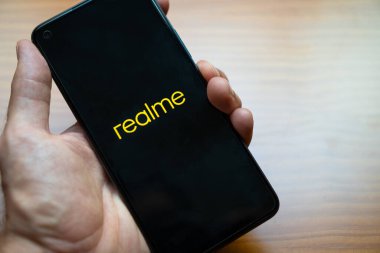 Yeni akıllı telefon Realme 8 'i açarken elinde tutan kişinin eli. Yeni android cep telefonu sunumu.