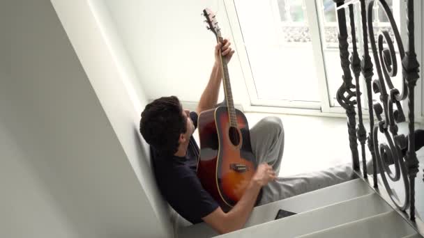 階段で自宅でアコースティックギターを演奏する男のトップビュー — ストック動画