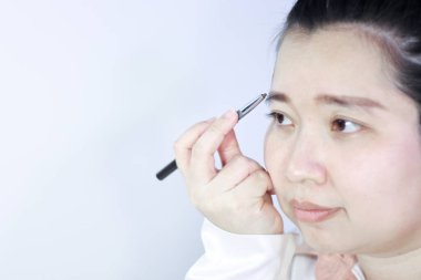 Bir kadın kaş kalemiyle kaşlarını çiziyor.