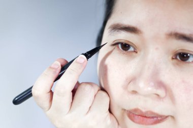 Bir kadın göz kapağına sürme kalem kullanıyor.