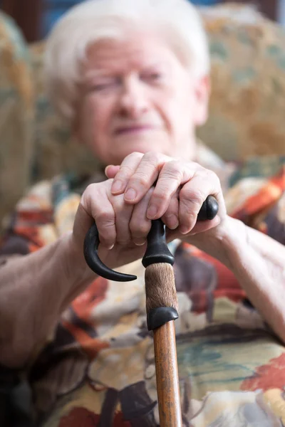 Old woman with her hands on a cane — Stock Photo, Image