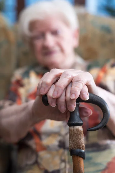 Oude vrouw met haar handen op een stok — Stockfoto