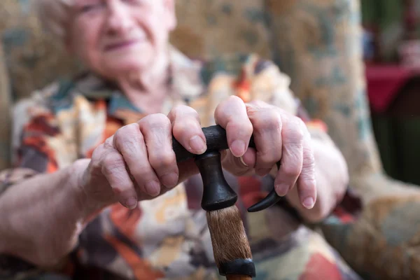 Vieja con las manos en un bastón — Foto de Stock