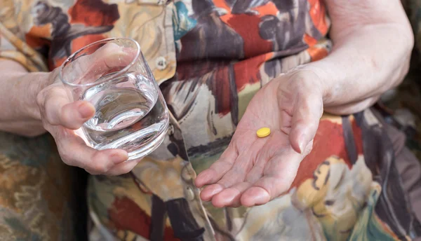 Old woman taking a pill — Stock Photo, Image