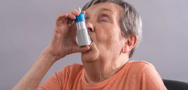 Ανώτερος γυναίκα χρησιμοποιώντας μια συσκευή εισπνοής — Φωτογραφία Αρχείου