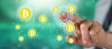 Bir adam dokunmatik ekranda bitcoin konseptine parmağıyla dokunuyor.
