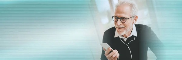 Senior businessman using earphones during conversation on mobile phone; panoramic banner