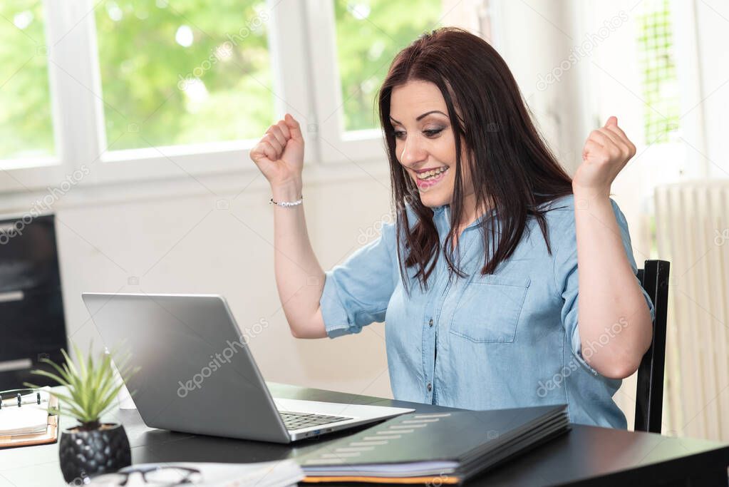 Young attractive woman getting good news on laptop