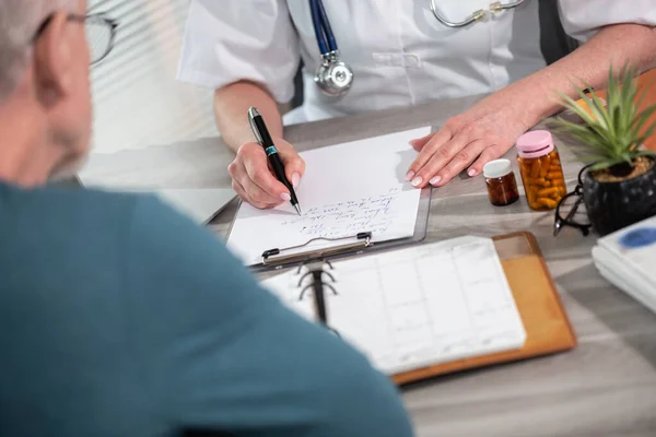 Female doctor writing prescription to her patient in medical office