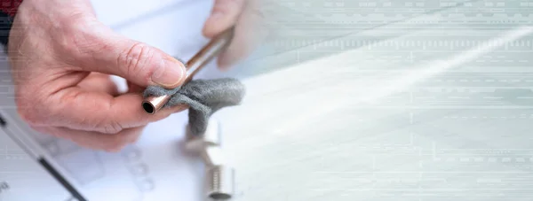 Plumber preparing a copper tube before welding; panoramic banner