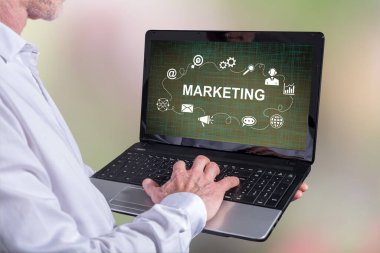 Adam ekranda pazarlama stratejisi olan bir dizüstü bilgisayar kullanıyor.