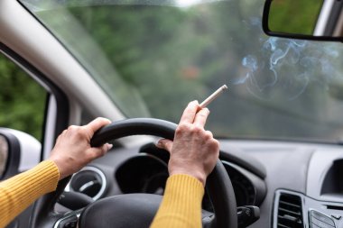 Araba kullanırken sigara içen kadın.