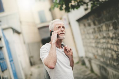 Olgun bir adam cep telefonunu açık havada kullanıyor.