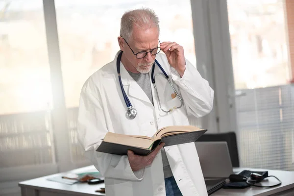 Ανώτερος Γιατρός Διαβάζει Ένα Βιβλίο Στην Κλινική — Φωτογραφία Αρχείου