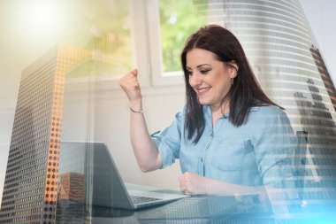 Genç ve çekici bir kadın laptoptan iyi haberler alıyor.