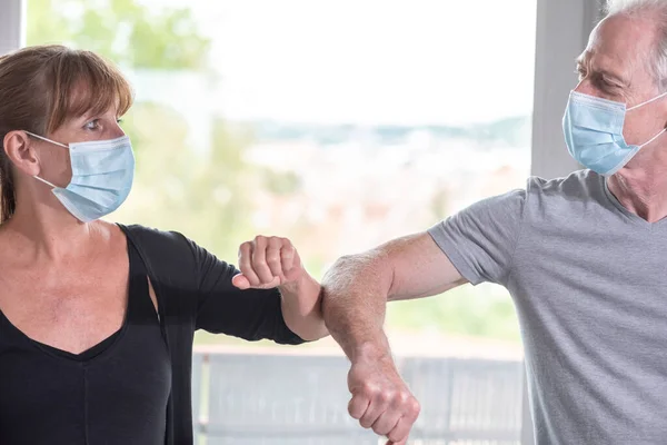 Mature man and woman having elbow greeting during covid outbreak