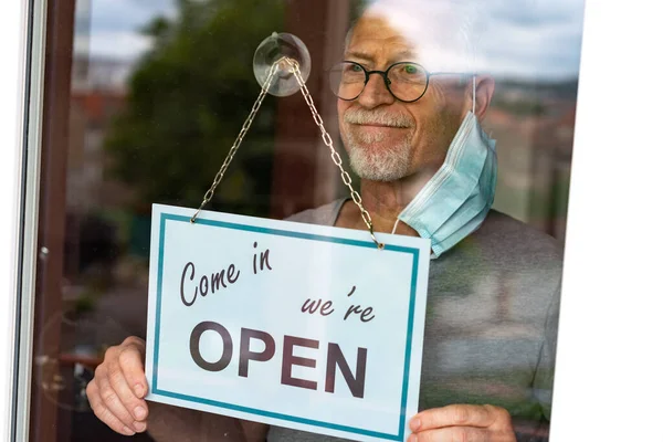 Store owner hanging come in we're open sign on window