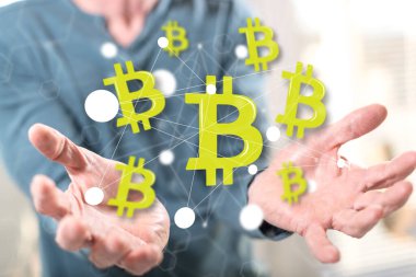 Bitcoin kavramı arka plandaki bir adamın ellerinden üstündür.