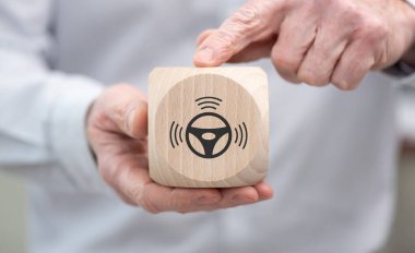 Hand holding a wooden cube with symbol of self-driving car concept