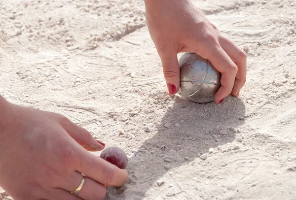 Les mains ramassant une boule de pétanque et le cric — Photo