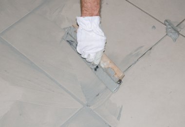 Tiler filling up joints with a rubber squeegee clipart