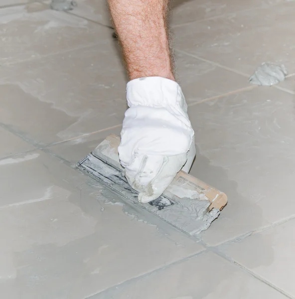 Tiler filling up joints with a rubber squeegee — Stock Photo, Image