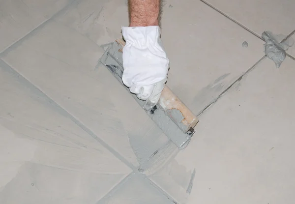 Tiler filling up joints with a rubber squeegee — Stock Photo, Image