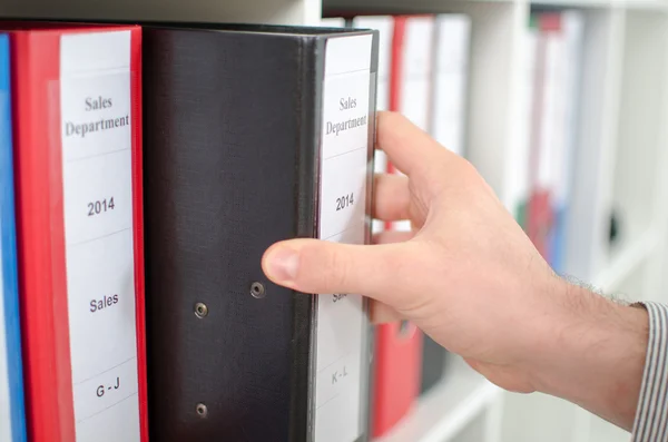 Mano sacando una carpeta de un estante — Foto de Stock