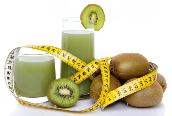 Composición con vasos de jugo de kiwi, kiwis frescos y una cinta m — Foto de Stock