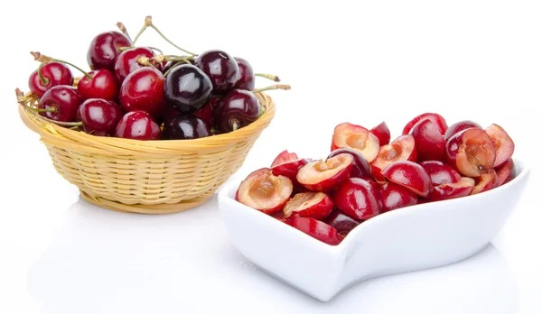 Cup of pitted cherries and whole cherries in a basket — Stock Photo, Image