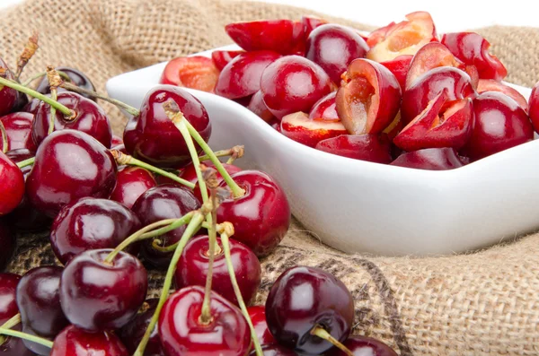 Cup of tasty pitted cherries and whole cherries — Stock Photo, Image