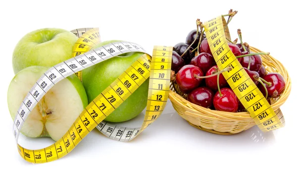 Green apples and a basket of cherries surrounded with a tape mea — Stock Photo, Image