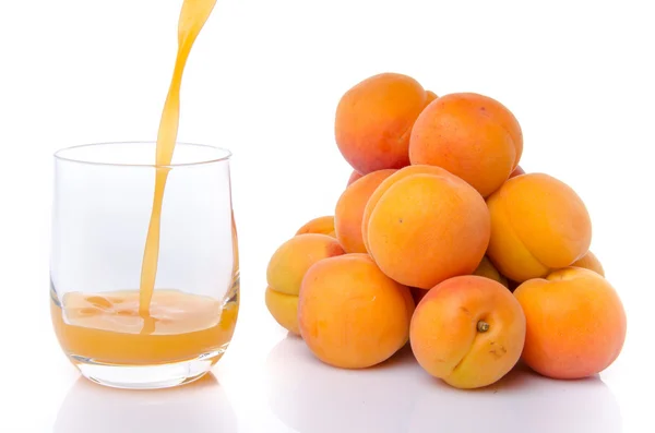 Apricot juice poured into a glass near a heap of apricots — Stock Photo, Image